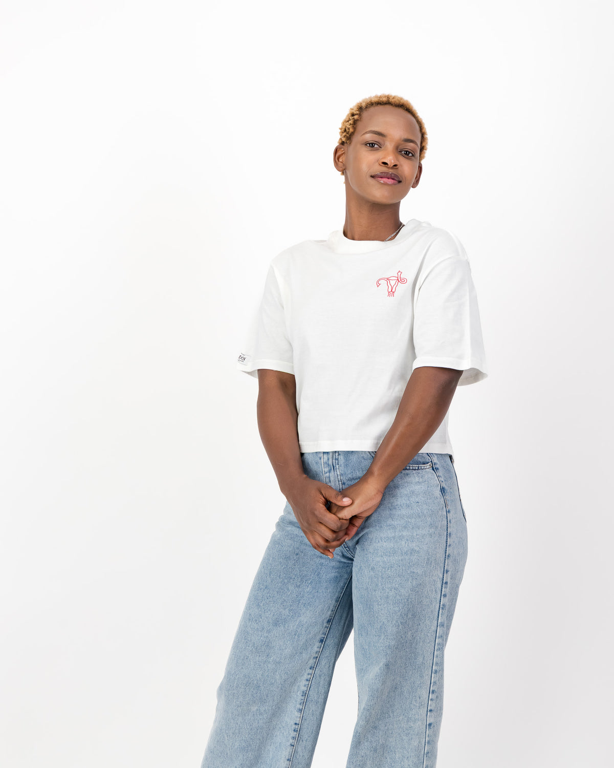 Woman wearing the white Uterus Zap tee with light blue jeans, front view