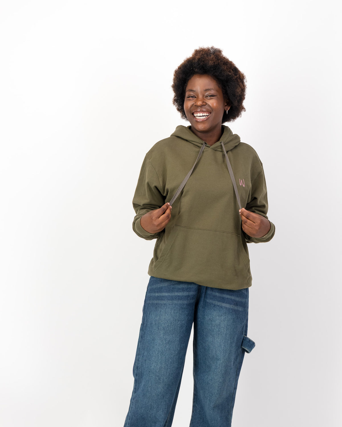 Smiling woman holding the drawstrings of the olive Pasta not Patriarchy hoodie, front view