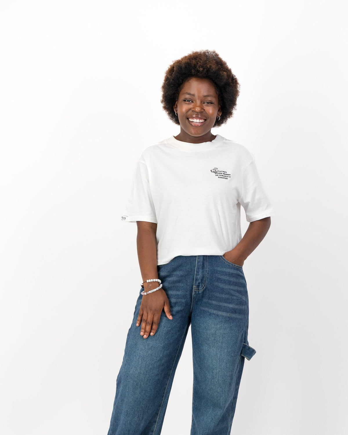 Woman wearing the white Cat Naps Because Smashing the Patriarchy is Exhausting tee with wide leg jeans, front view