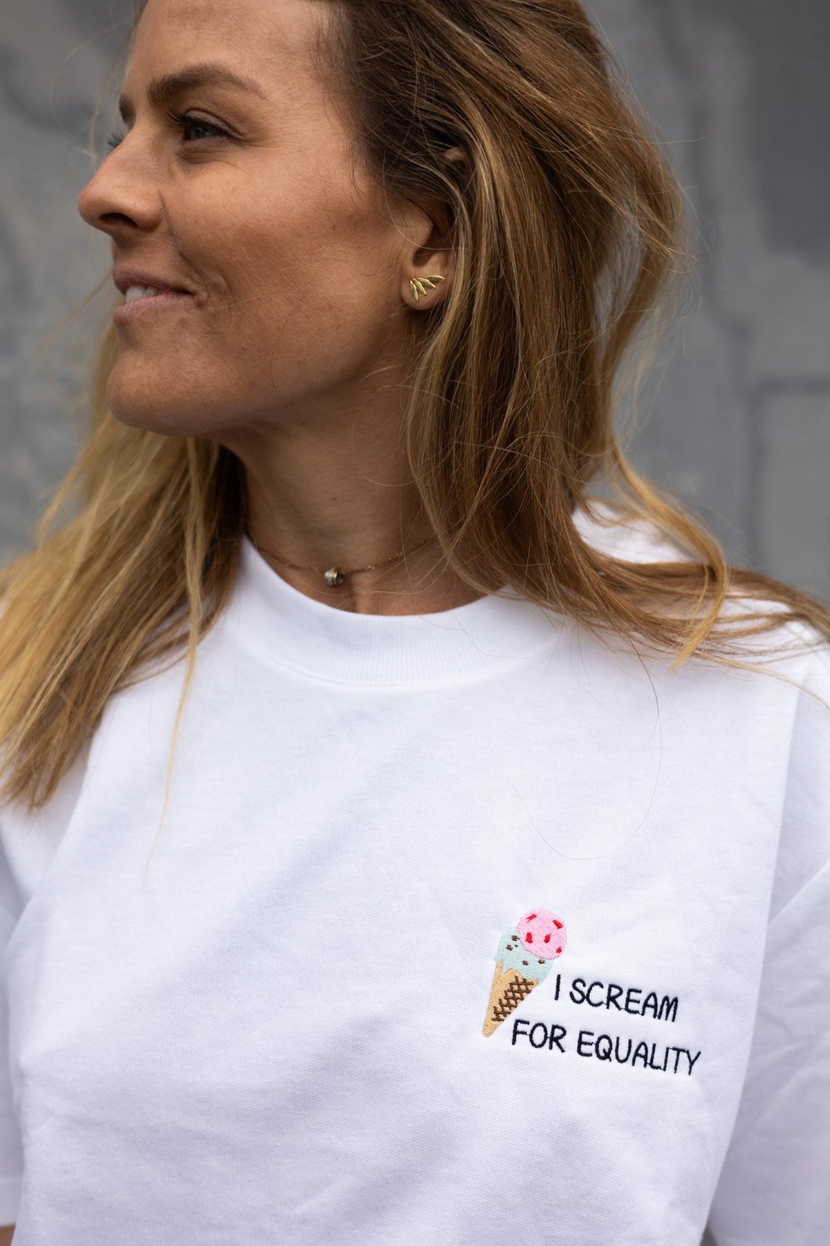 Woman looking over her shoulder in the white I Scream for Equality tee, chest embroidery in view