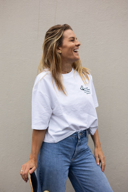 Laughing woman leaning on a skateboard in the white Cat Naps tee and light blue jeans