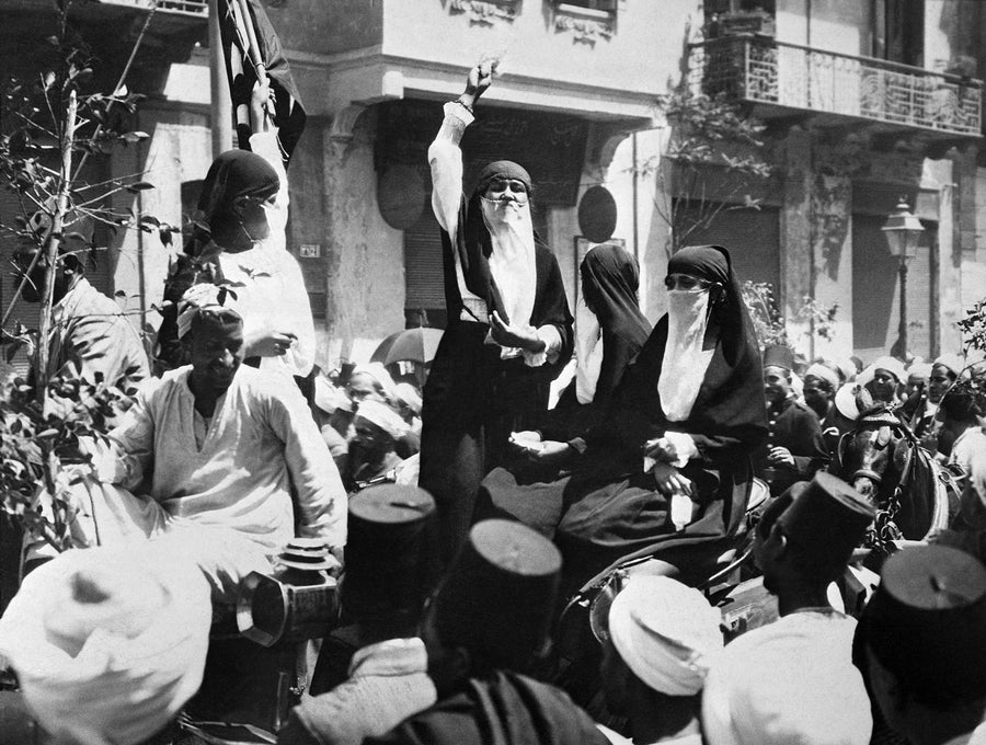Veiled women addressing a crowd from a carriage during the 1919 protests in Cairo, one with her fist raised