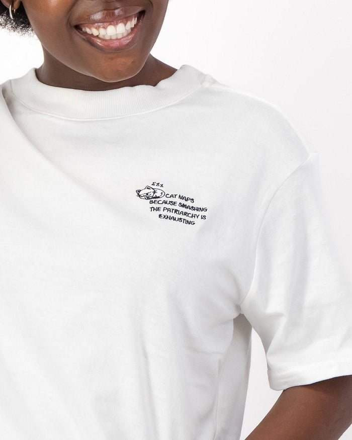 Close up of the sleeping cat embroidery and Cat Naps Because Smashing the Patriarchy is Exhausting slogan on the white tee