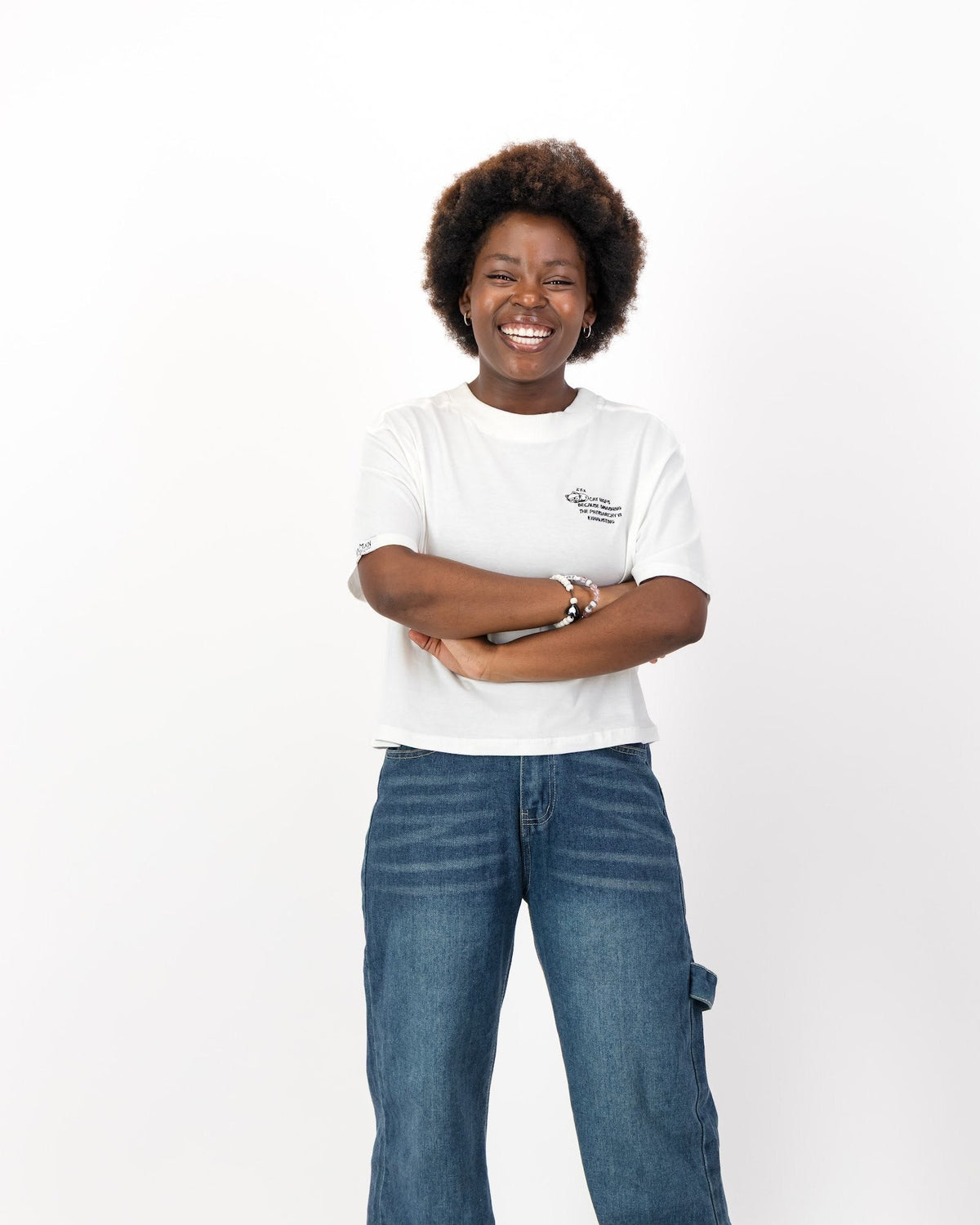 Smiling woman with her arms crossed in the white Cat Naps Because Smashing the Patriarchy is Exhausting tee