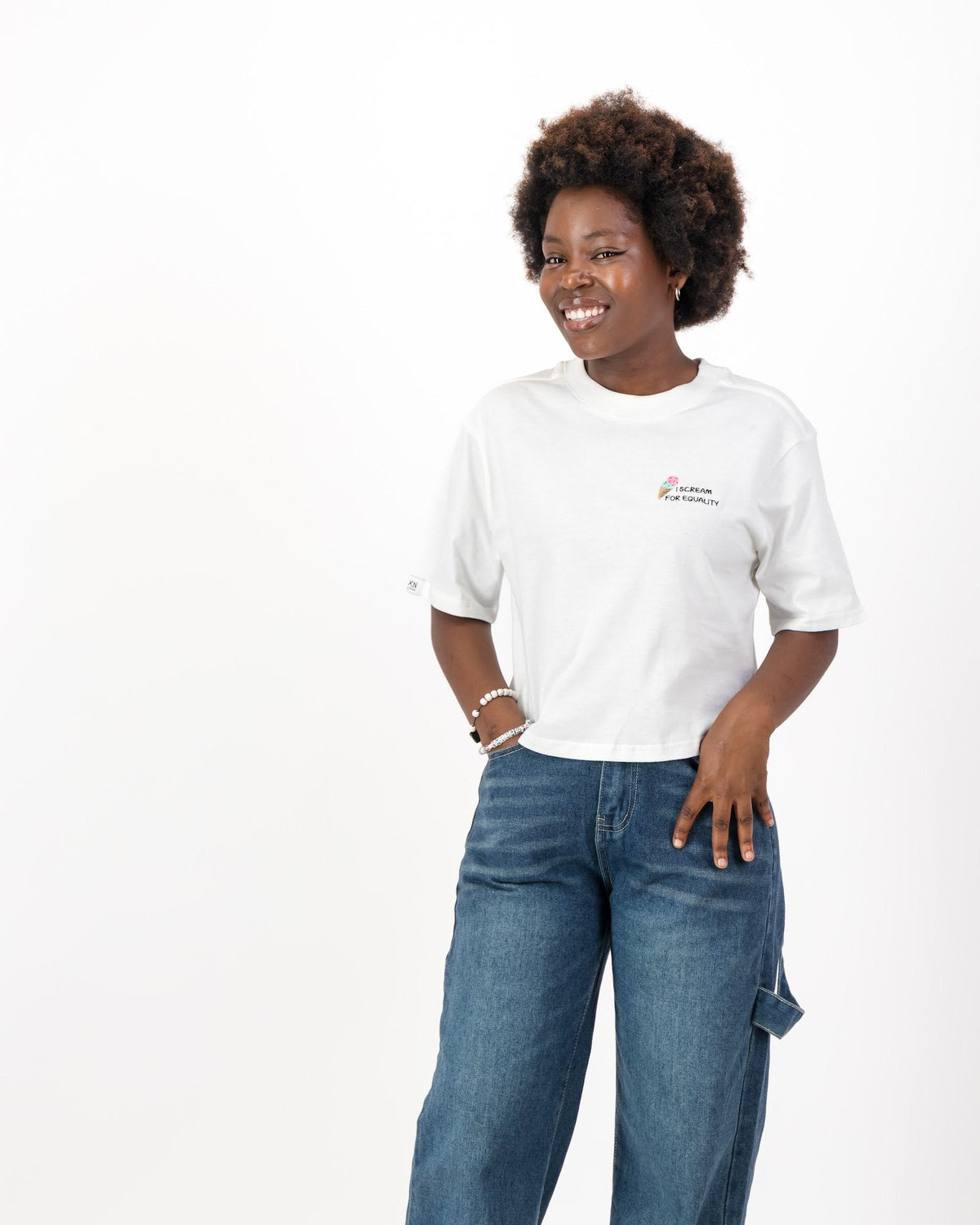 Smiling woman wearing the white I Scream for Equality tee with wide leg jeans, front view