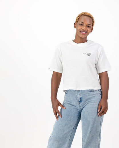 Woman wearing the white I'll Smile When You're Funny tee with light blue jeans, front view