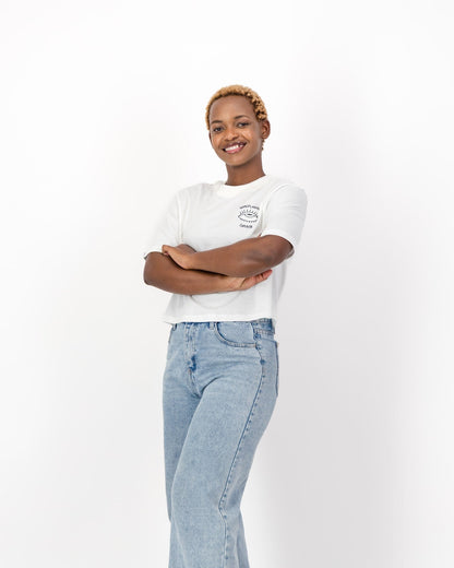 Smiling woman with her arms crossed in the white Mansplaining Survivor tee and jeans