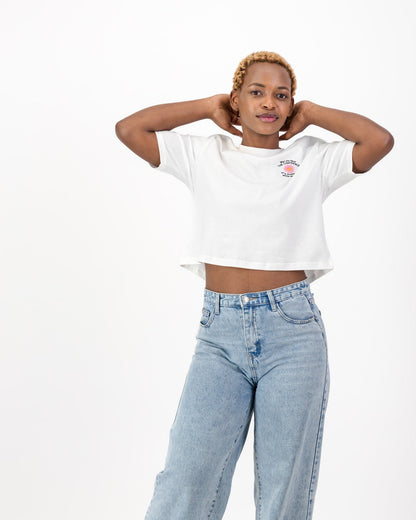 Woman with her arms raised behind her head in the white May You Have the Confidence of a Mediocre White Man tee and light blue jeans