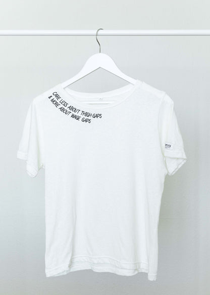 The white Care Less About Thigh Gaps and More About Wage Gaps tee on a hanger