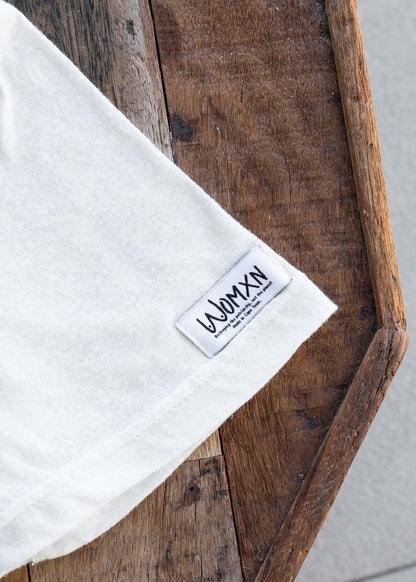 Close up of the woven WOMXN label on the hem of the white Care Less About Thigh Gaps tee