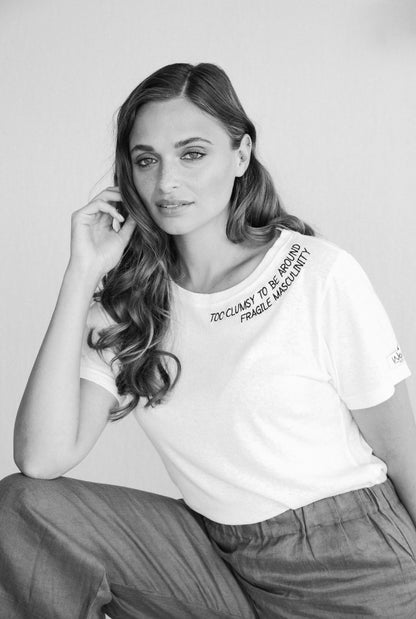 Black and white photo of a woman touching her hair in the Too Clumsy to be Around Fragile Masculinity tee, slogan along the collar